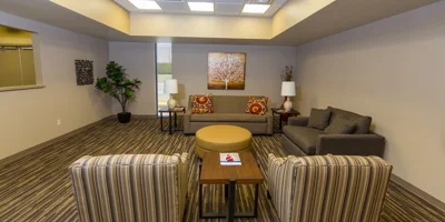 Indoor waiting area with striped armchairs and a central round ottoman