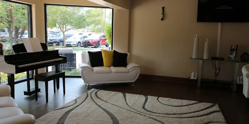 Lounge area with white couches, large windows and a piano.