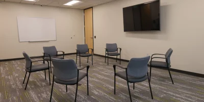 Therapy room with chairs arranged in a circle and a whiteboard.