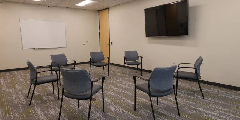 Therapy room with chairs arranged in a circle and a whiteboard.
