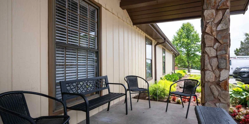 Covered outdoor seating area with black chairs and a stone column.