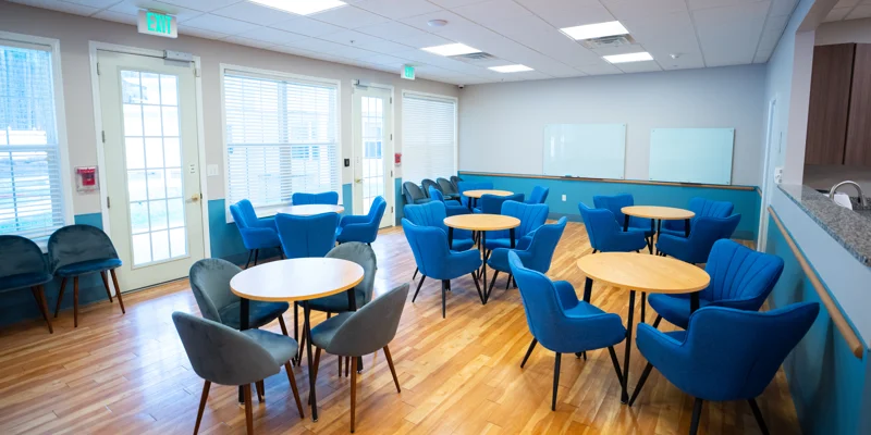 Bright group room with blue chairs and round tables