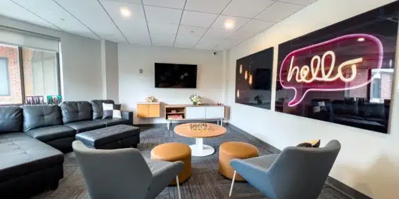 A cozy lounge with modern furniture and a neon "hello" sign.