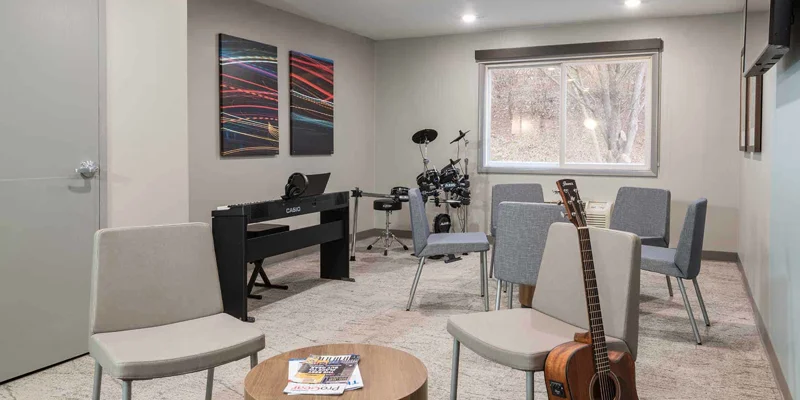 A music therapy room with chairs, a keyboard, and a drum set.