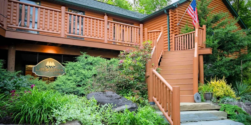 The entrance to a log-style rehab center with lush landscaping