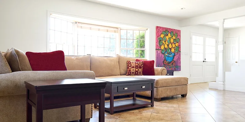 A living room with a sectional sofa, coffee tables, and large windows.