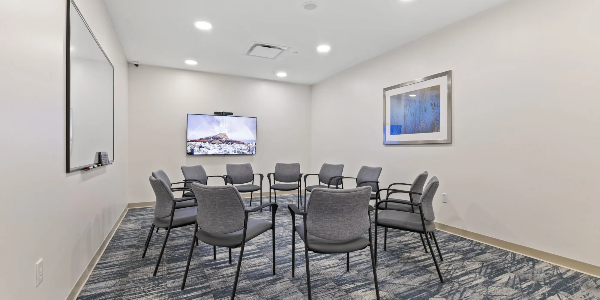 A group therapy room with chairs arranged in a circle and a TV screen.