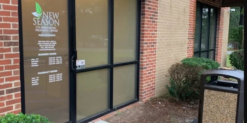 Entrance of New Season Treatment Center with a glass door and brick walls.