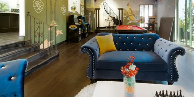 Lounge area with blue tufted couch and arcade games