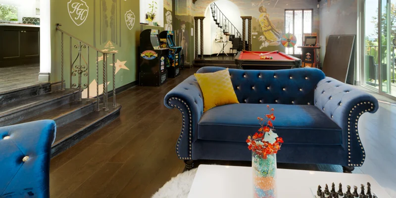 Lounge area with blue tufted couch and arcade games