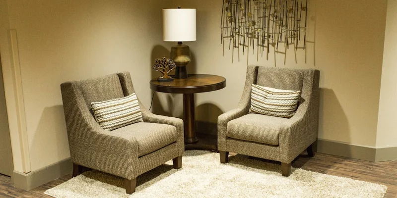 A cozy seating area with two beige armchairs and a small table