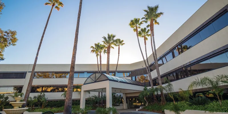 The exterior of a modern rehab facility with palm trees and greenery