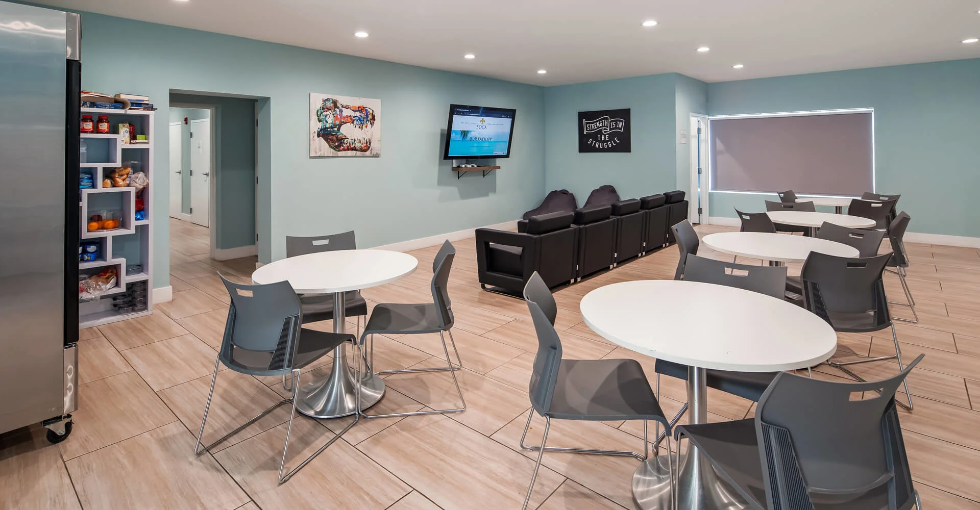 Lounge area with tables, seating, snacks, and a large TV.