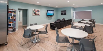 Lounge area with tables, seating, snacks, and a large TV.