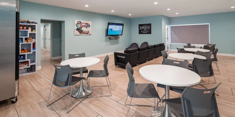 Lounge area with tables, seating, snacks, and a large TV.