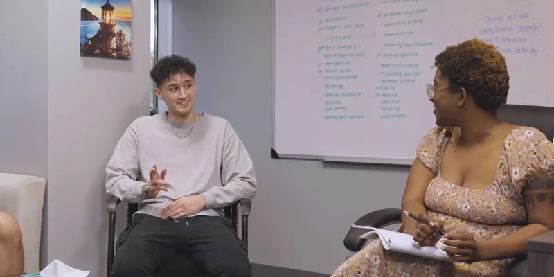 People in a therapy session with whiteboard backdrop.