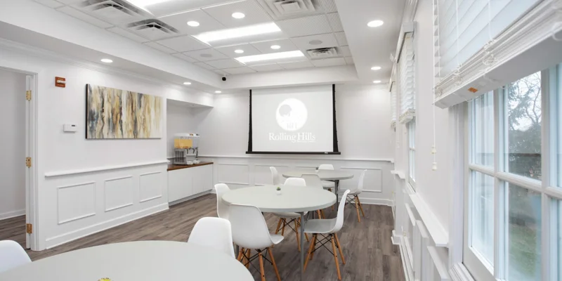 Dining area with  tables and chairs in front of a projector screen.