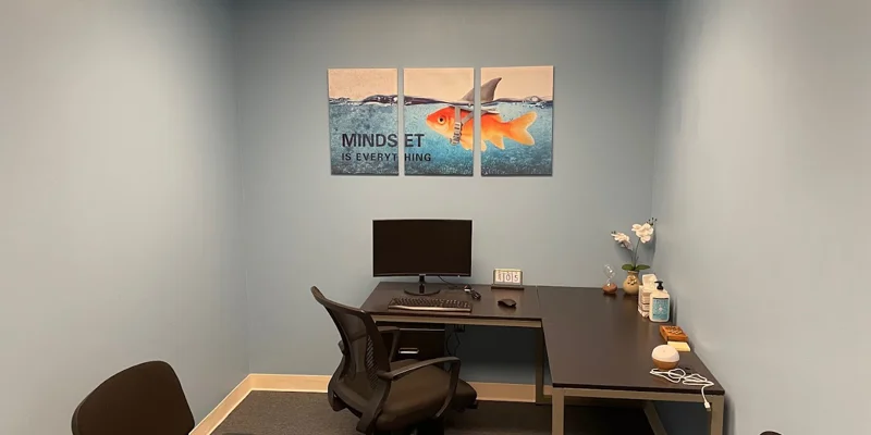 Therapy room with a computer desk, chairs, and artwork.