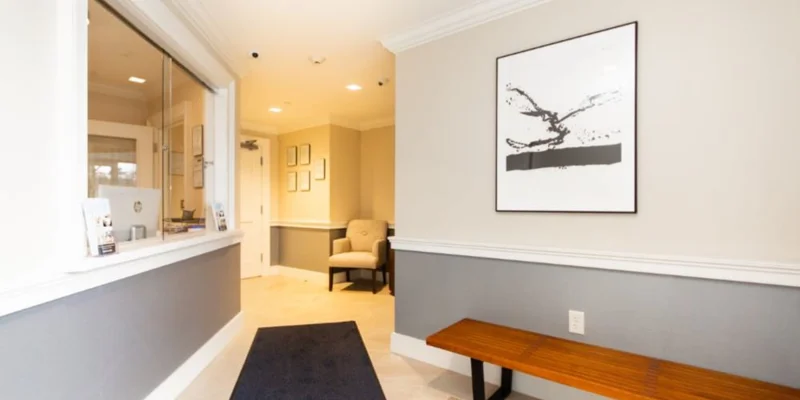 Lobby with  chairs, reception desk window.