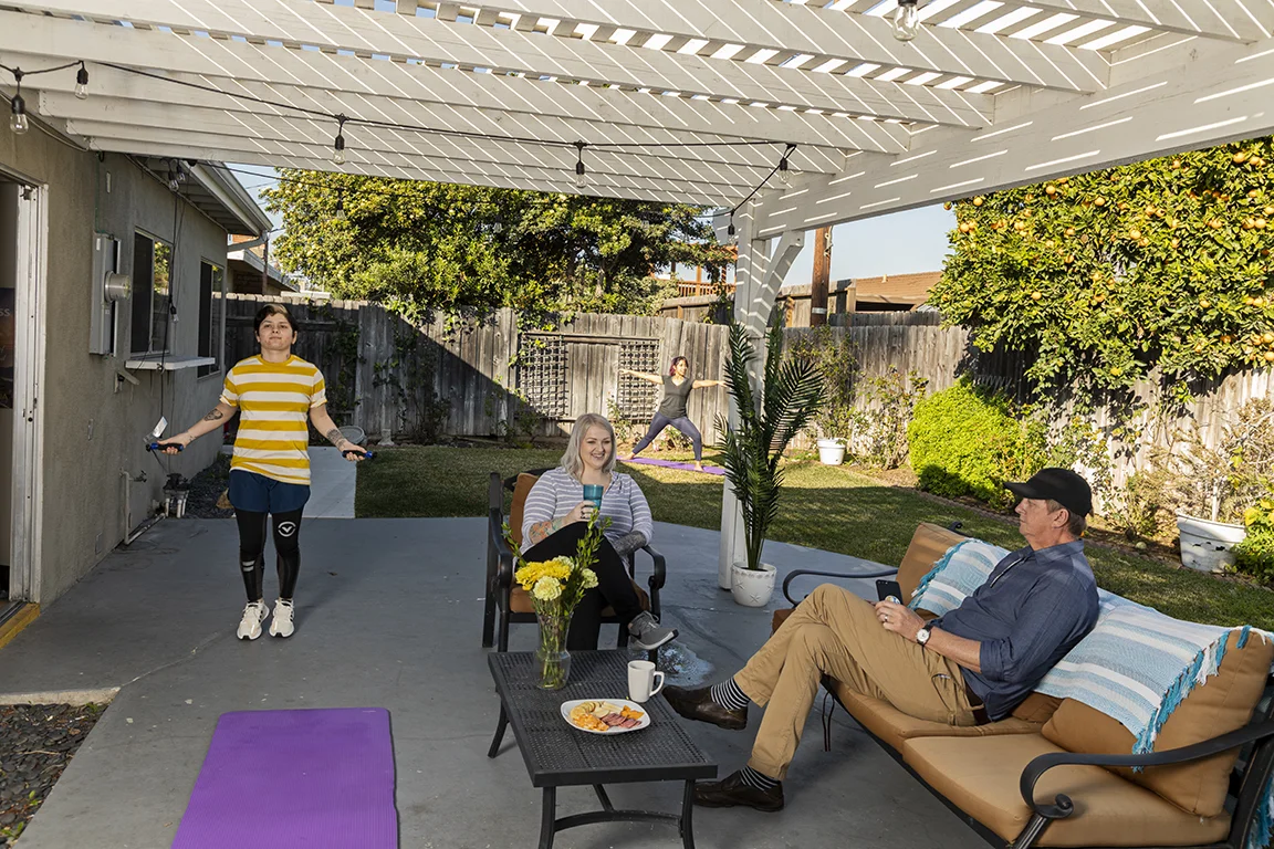 Rehab facility backyard with a covered patio, seating, and greenery.