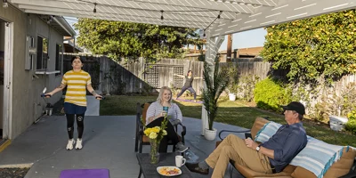 Rehab facility backyard with a covered patio, seating, and greenery.