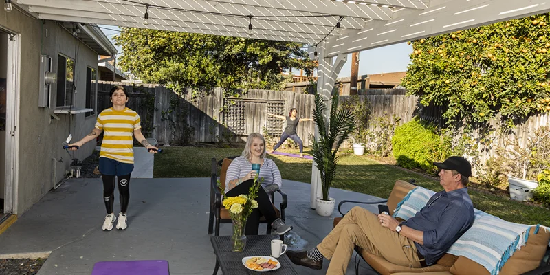 Rehab facility backyard with a covered patio, seating, and greenery.