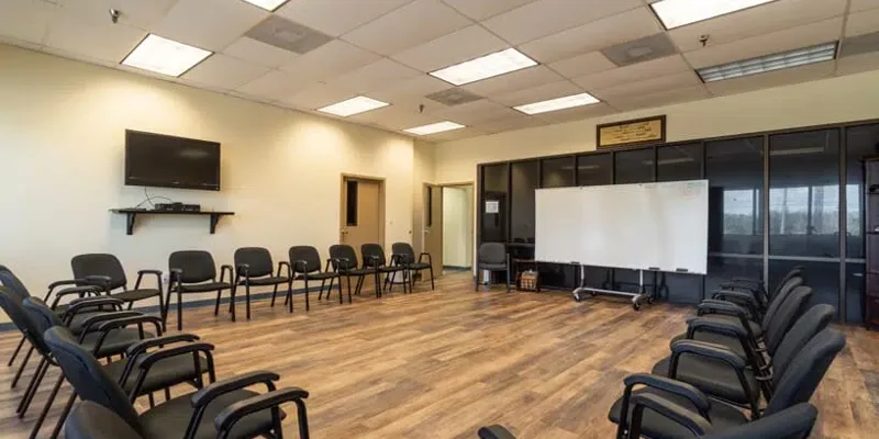 Group therapy room arranged with chairs in a circle, a whiteboard, and a TV.