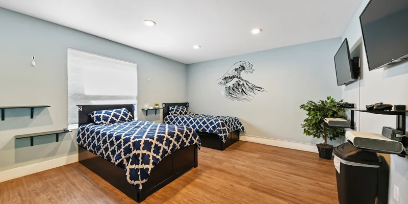 Bedroom with matching twin beds, wave wall art, and gaming shelves.