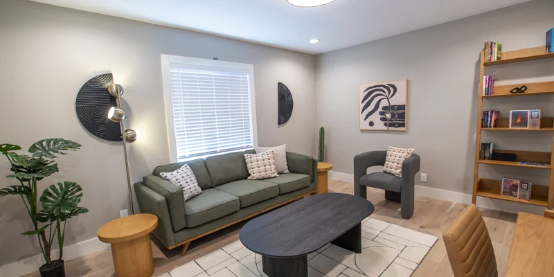 Stylish seating area with a green sofa, bookshelves, and artwork