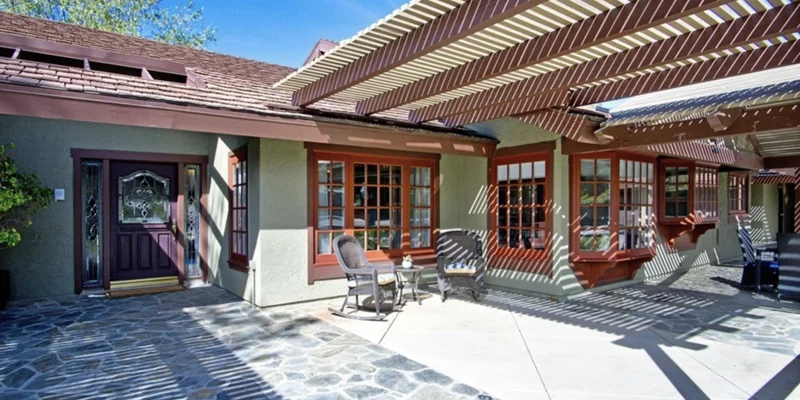 Entrance with a stone patio and pergola.