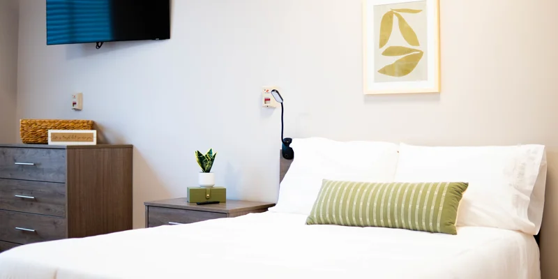 Modern rehab bedroom with a TV, nightstand, and decor.