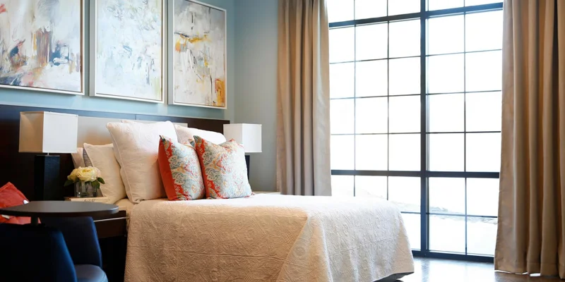 Stylish bedroom with a large window and abstract paintings.