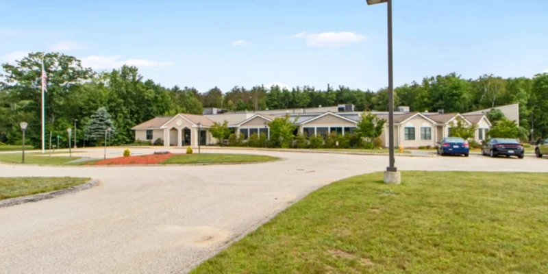 Exterior with a circular driveway, parking and trees.