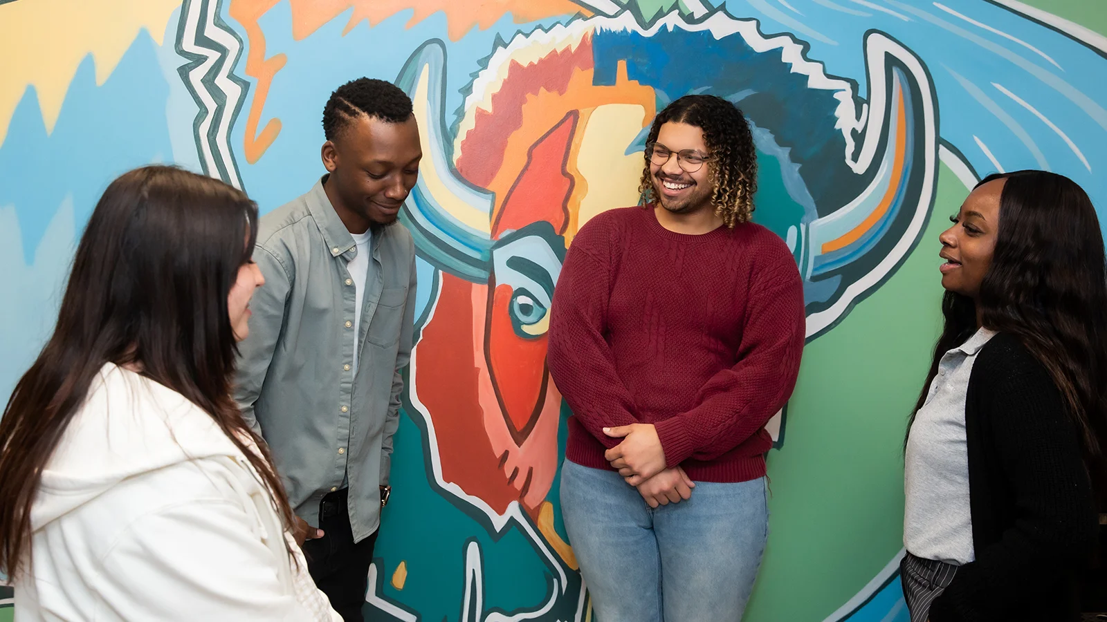 roup of four people near a colorful mural.