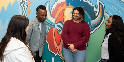 roup of four people near a colorful mural.