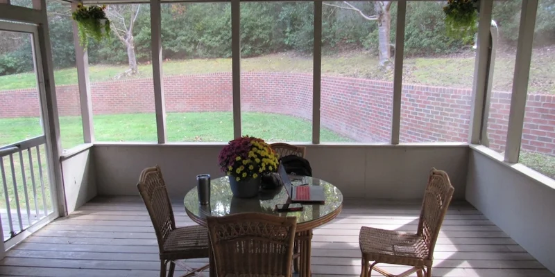 A screened-in porch with a table and chairs