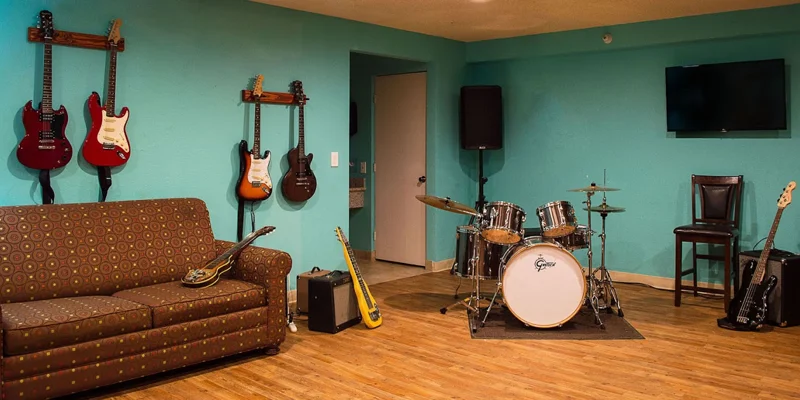 Music therapy room with guitars, a drum set, and seating.