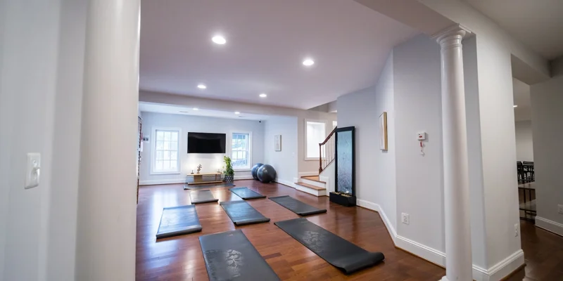 A bright fitness space with yoga mats and a large TV in the background