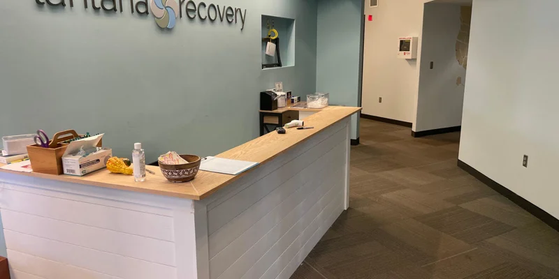 Reception area with a light wood desk and a "Lantana Recovery" sign