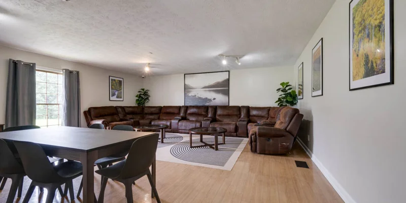 Lounge area with a large brown sectional sofa, dining table, and decor.