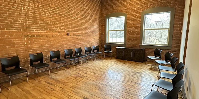 Group meeting space with black chairs along brick walls