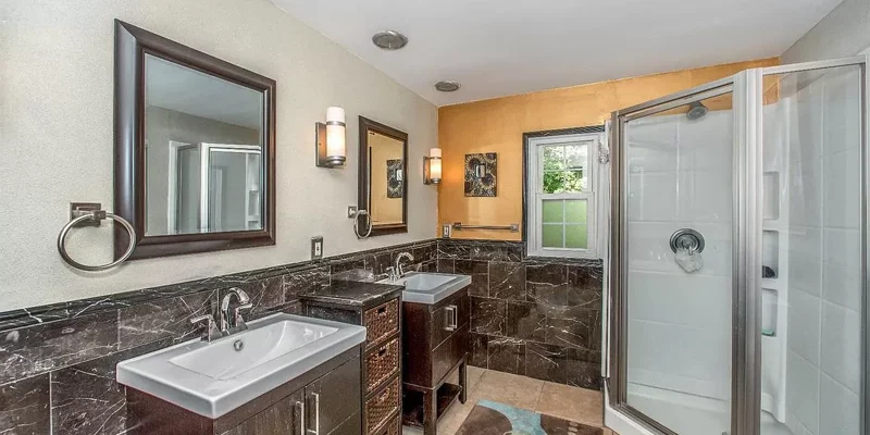Bathroom with stylish tiles, two sinks, and a walk-in shower.