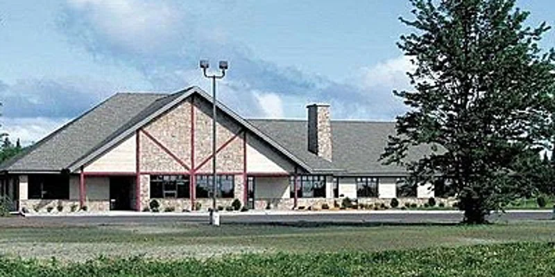 A rehab facility with a large sloped roof and a surrounding natural landscape