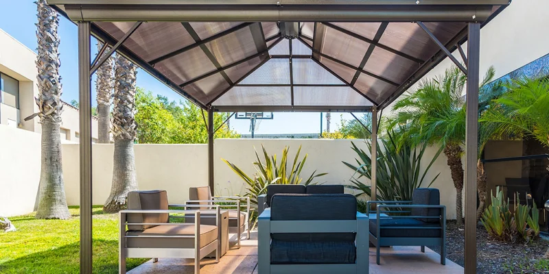 A shaded outdoor seating area with cushioned chairs and tropical plants