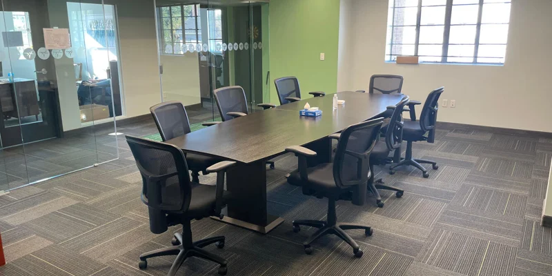 A spacious meeting room with a long table and office chairs