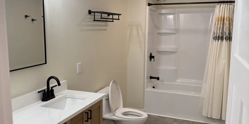 Modern bathroom with white tub, black fixtures, and sink vanity.