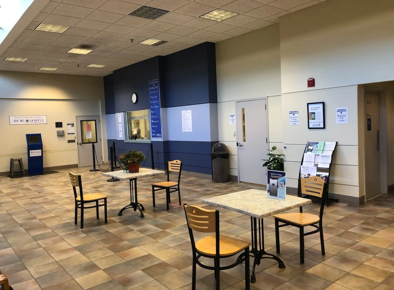 Lobby with wooden chairs around tables, and potted plants.
