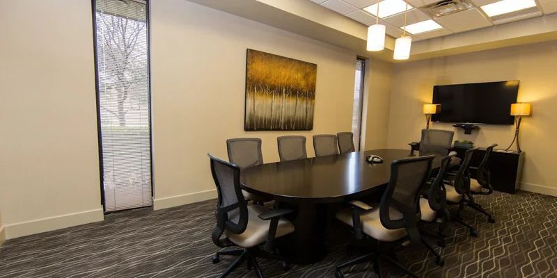Conference room with a large black table, chairs, and a mounted TV