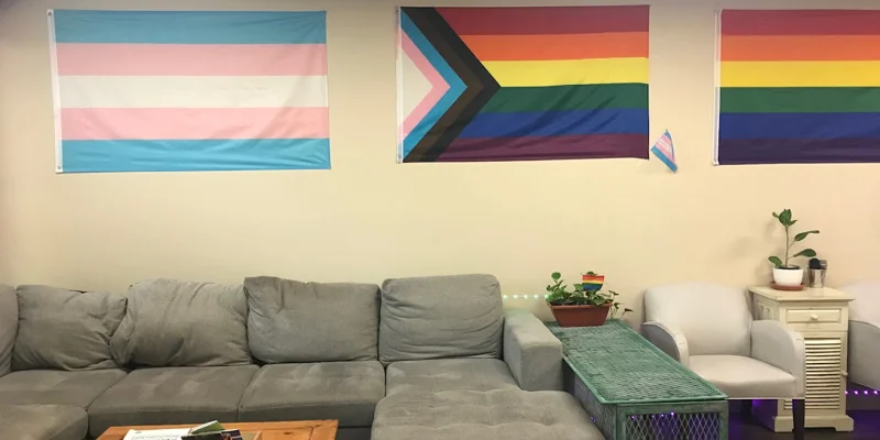 A lounge with gray sofas and pride flags on the walls