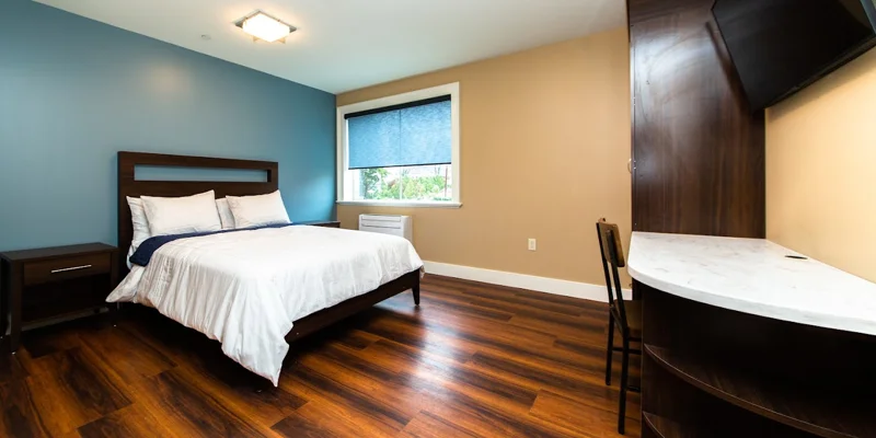 Bedroom with a window, wooden decor and side-table.